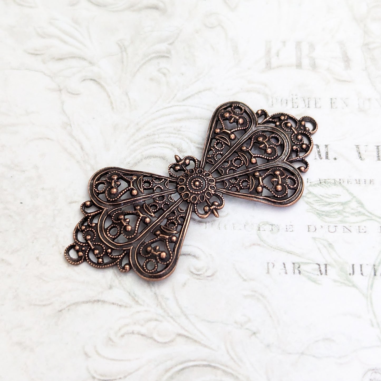 bow-shaped filigree in antiqued copper-plated brass with intricate cut-out design