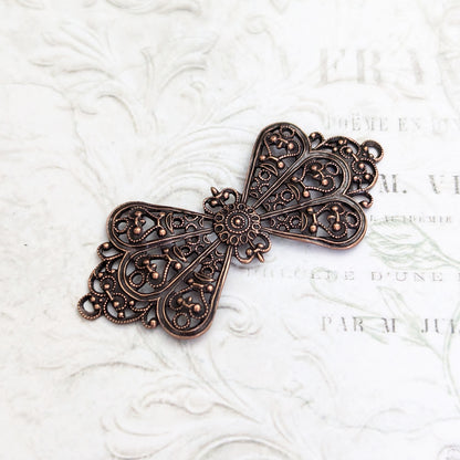 bow-shaped filigree in antiqued copper-plated brass with intricate cut-out design