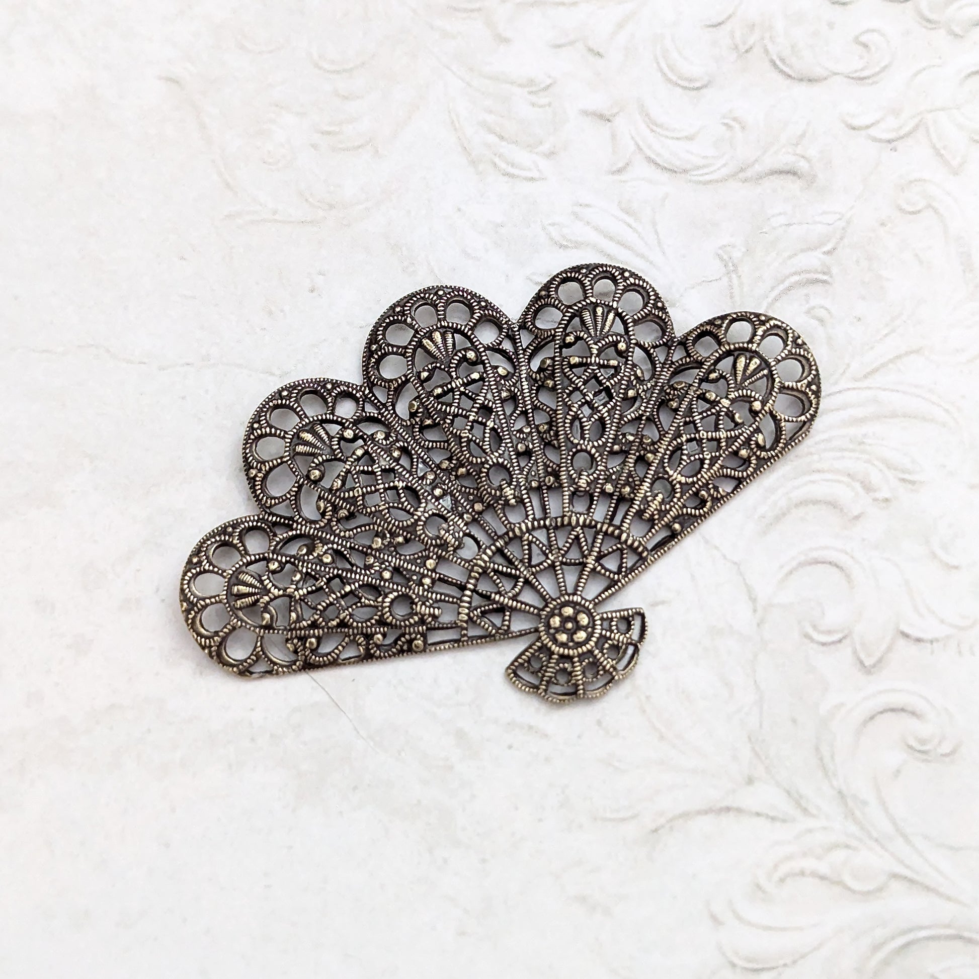 An antiqued brass fan-shaped filigree